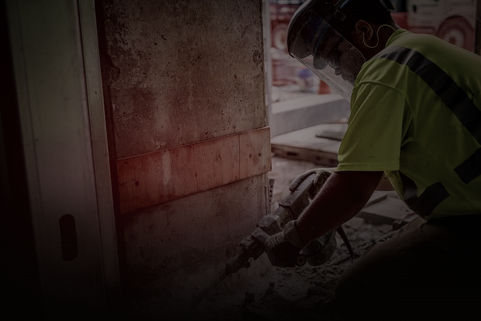 Camera operator filming a tradesperson breaking concrete on a jobsite