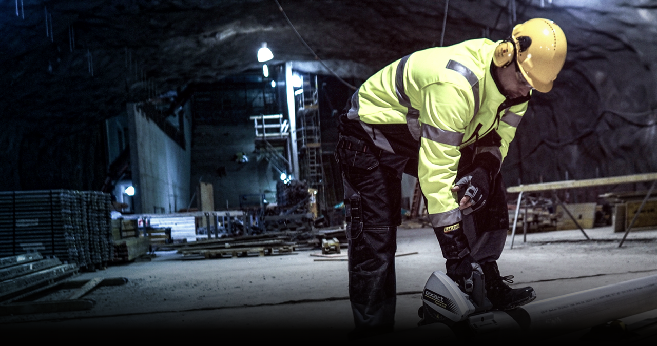 Tradesperson cutting pipe with a saw in a dark tunnel